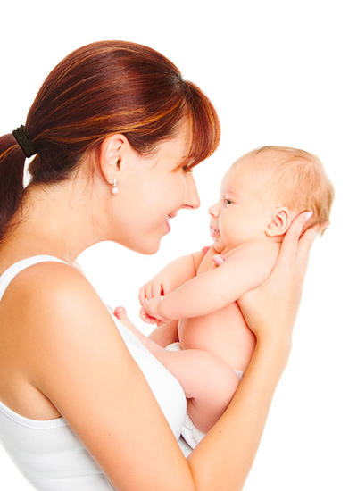 Mère aux cheveux roux tenant son nouveau-né dans ses bras et lui souriant